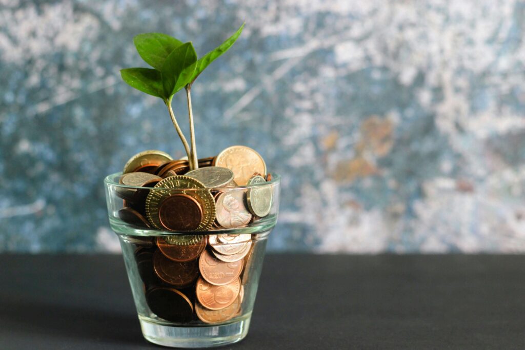 Glass jar filled with coins and a growing green plant symbolizing financial growth and compound interest